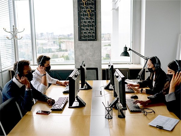 An iFOVS support team working at their desks with headsets