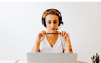 A support professional working at a laptop wearing a headset