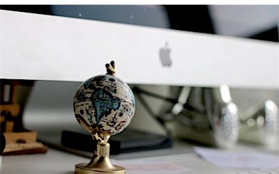 A travel desk workstation with a globe beside the computer