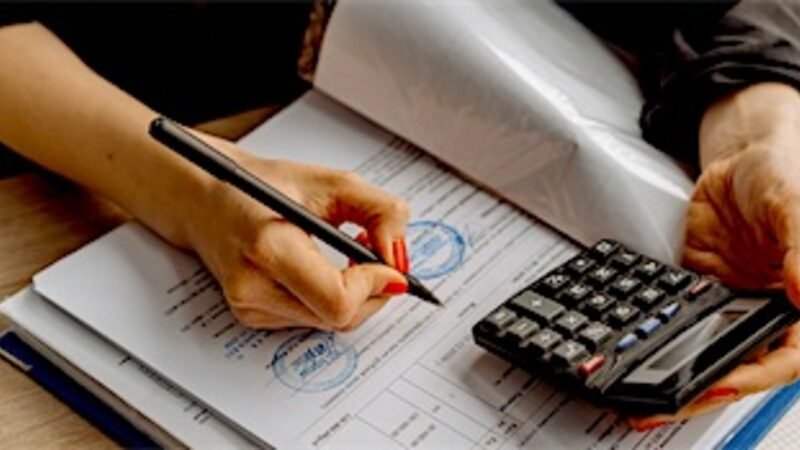 A payroll calculation being worked through on paper beside a calculator