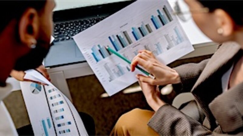 Two people comparing printed charts side by side across a table