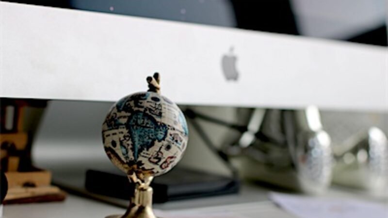 A world globe on a desk beside a computer, representing offshore regions
