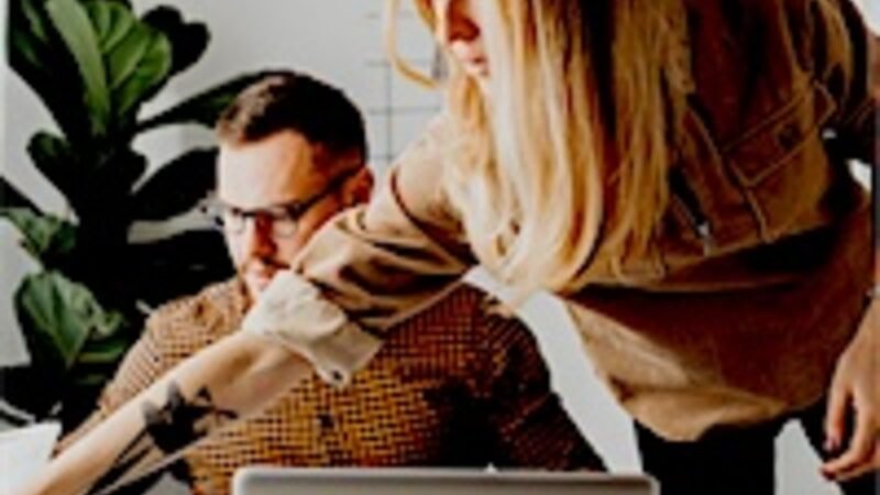 A small team working together around a laptop in an office